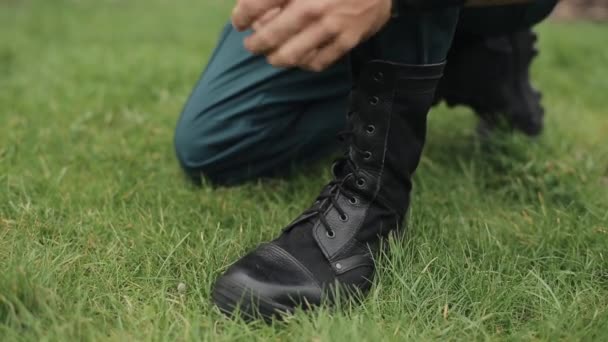 Primer plano. Manos masculinas atando cordones de sus botas altas de cuero negro al aire libre — Vídeos de Stock