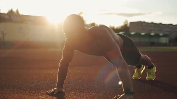 A close-up side view of a young muscular bodybuilder pumping up arms with a barbell — Stock Video