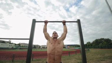 Sallanan bacağı olan zinde genç adam spor salonundaki yatay çıtayı yükseltiyor.