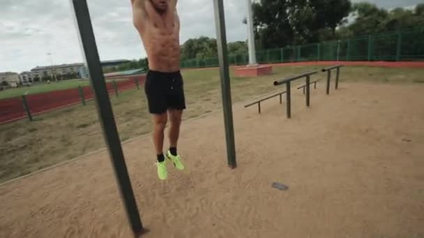 Passform ung man gör hängande ben höjer motion på horisontell bar i gatan gym — Stockvideo
