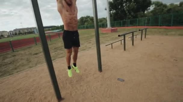 Ajuste joven haciendo colgar la pierna plantea ejercicio en la barra horizontal en el gimnasio de la calle — Vídeos de Stock