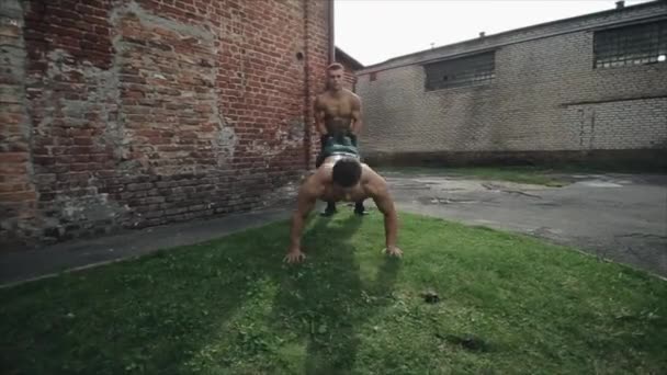 Dos deportistas en forma haciendo ejercicio carretilla a pie con doble palmada en verano al aire libre — Vídeo de stock