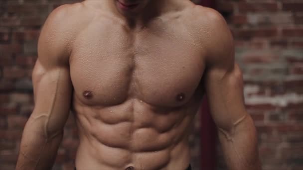 Gros plan du corps masculin nu en sueur musculaire après l'entraînement. Fond en brique rouge — Video