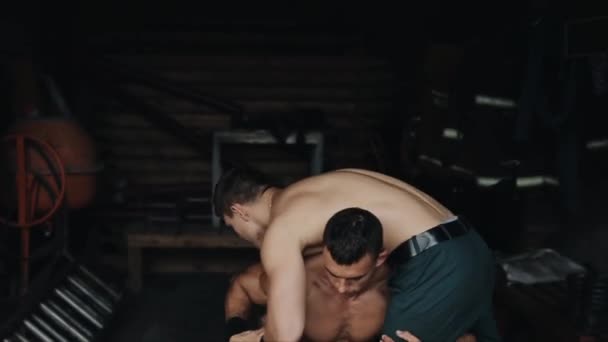 Blízký pohled na silného muže bez košile, jak dřepí s dalším svalnatým mužem na ramenou. — Stock video
