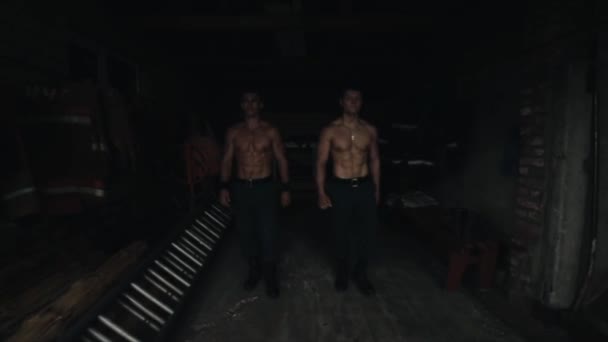 Un paio di brutali uomini a torso nudo che vanno dritti dentro un piccolo edificio buio. Passare dalle tenebre alla luce. Rallentatore — Video Stock