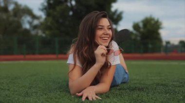 Güneş gözlüklü genç bir kadın dışarıda sabun köpüğü üflüyor ve etrafında dönüyor. Yakın görüş. Ağır çekim. Kız gülüyor. Son moda turuncu güneş gözlüklü kız