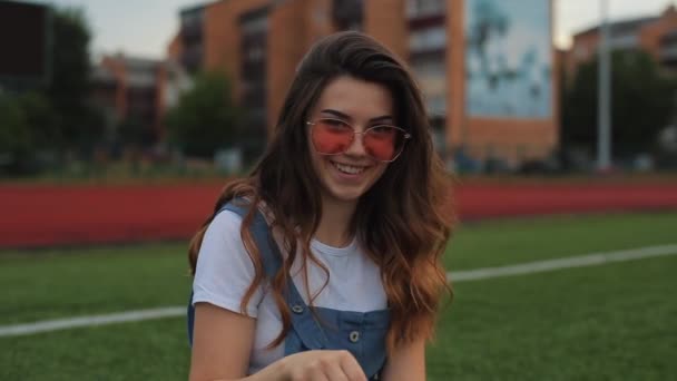 Mulher bonita em óculos de sol soprando bolhas de sabão ao ar livre e girando ao redor. Vista próxima. Movimento lento. menina na moda óculos de sol laranja — Vídeo de Stock