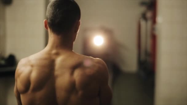 Hombre guapo sin camisa haciendo ejercicios de cuerda de batalla con dos mangueras de fuego. Vista trasera. Vista cercana de medio cuerpo — Vídeos de Stock