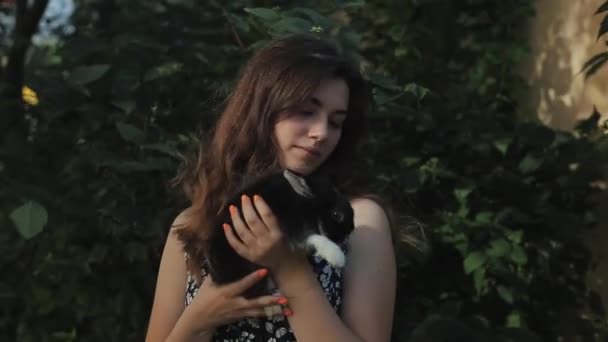 Cerca vista lateral de la joven hermosa mujer besando lindo conejito al aire libre — Vídeos de Stock