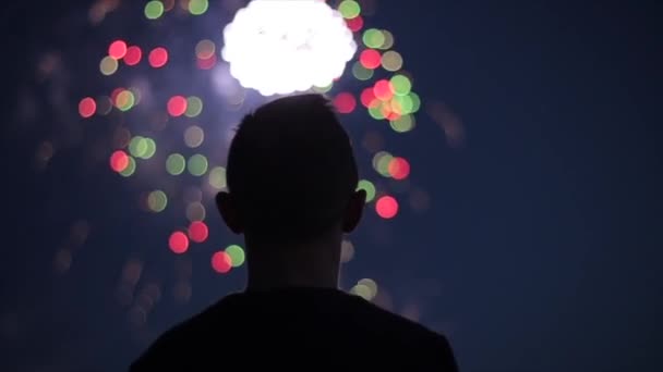 Silueta borrosa de primer plano de un hombre disfrutando de fuegos artificiales por la noche — Vídeo de stock