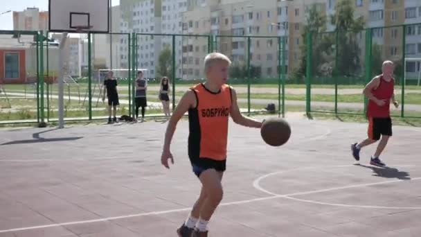 Бобруйск, Беларусь - 12 августа 2019 года: Подросток-уличный баскетболист защищает мяч, бросает его в корзину и пропадает без вести — стоковое видео