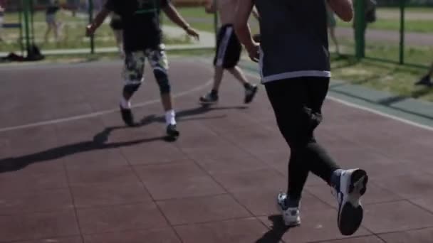 Bobruisk, Białoruś - 12 sierpnia 2019: Wolny ruch. Z bliska. Młody uliczny koszykarz prowadzi piłkę, podczas gdy inni gracze próbują mu ją odebrać — Wideo stockowe