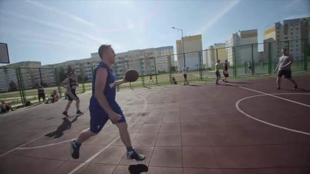 Бобруйск, Беларусь - 12 августа 2019 года: Медленное движение. Счастливый баскетболист ведет и передает мяч во время игры в уличный баскетбол — стоковое видео