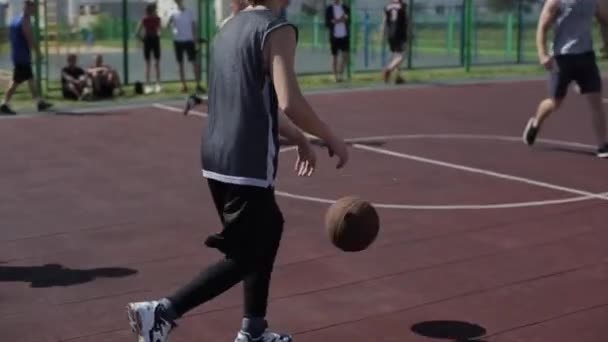 Bobruisk, Belarus - 12 augustus 2019: slow motion. Straatbasketbalspeler dribbelt en verdedigt bal. Kogel in de mand gooien — Stockvideo