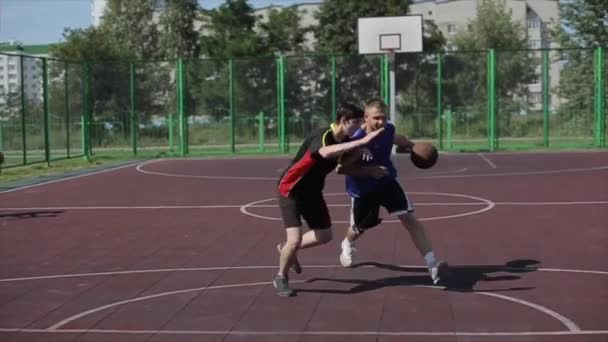 Bobruisk, Belarus - 2019 년 8 월 12 일 : slow motion. 길거리 농구 선수가 드리블하고 수비하는 공을 가지고 있습니다. 공을 바구니에 던진다 — 비디오