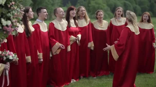 Minsk, Bielorrusia - 24 de agosto de 2019: Un grupo de jóvenes con túnicas rojas interpretan una canción en verano al aire libre — Vídeos de Stock