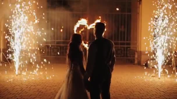 Minsk, Belarus - August 8, 2019: Back view of just married couple looking at a burning heart and fireworks, turning around and embracing each other. Slow motion — Stok video