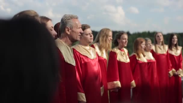 Минск, Беларусь - 24 августа 2019 года: Близкий обзор взрослых в красной одежде, поющих в евангельском хоре снаружи — стоковое видео