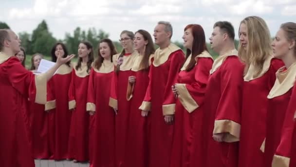 Minsk, Bielorussia - 24 agosto 2019: Vista da vicino degli adulti in abiti rossi che cantano in un coro gospel fuori — Video Stock