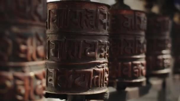 A close-up of a spinning buddhist prayer wheel in a row of wheels in Nepal Kathmandu — Stockvideo