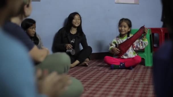 Kathmandu, Nepal - 14 November 2019: Beautiful Asian Nepalese Indian girls sitting in a circle on the floor singing, clapping and smiling. Casual warm clothes. Poverty. — Αρχείο Βίντεο