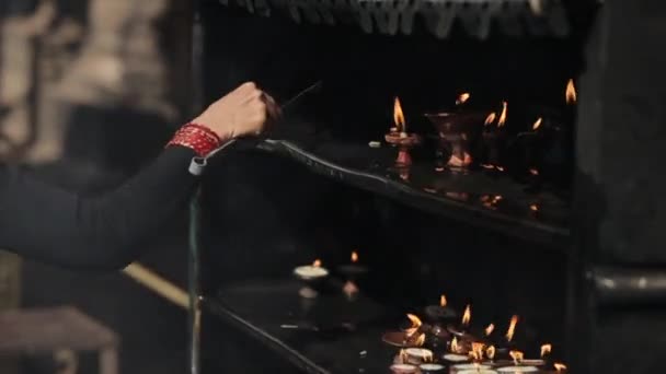 Un primer plano de una mujer nepalesa colocando velas encendidas, lámparas de mantequilla. Katmandú Nepal. Atrás, vista trasera . — Vídeo de stock