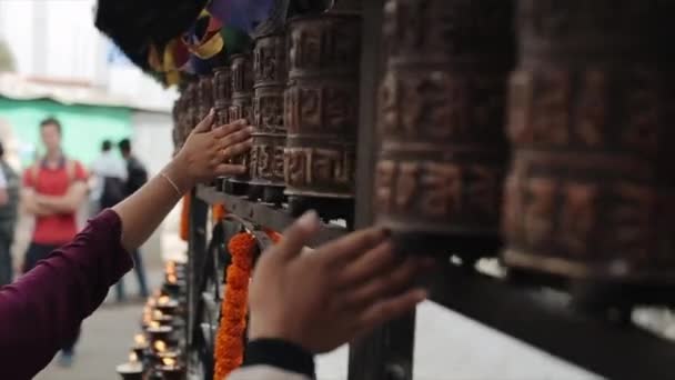 Pohled zblízka na nepalské lidi, kteří točí modlitebními koly. Nepál Káthmándú. Ruce. Svíčky a modlitební vlajky v pozadí. — Stock video