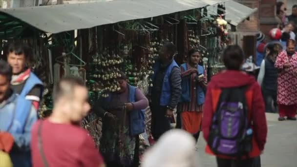 Katmandú, Nepal - 14 de noviembre de 2019: Una multitud de nepaleses, gente india caminando, pasando por un mercado local. Ciudad Katmandú, Nepal. Mercado tradicional, auténtico. Personas que venden artesanías . — Vídeos de Stock