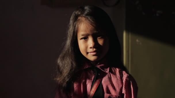 Katmandú, Nepal - 14 de noviembre de 2019: Una linda niña asiática nepalesa mirando y sonriendo a la cámara. Soleado. Luz suave. En interiores, en casa. Cabello caído . — Vídeo de stock