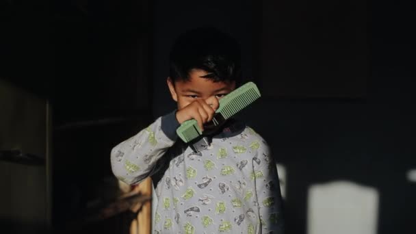Kathmandu, Nepal - 14 de novembro de 2019: Um menino asiático nepalês bonito penteando, escovando o cabelo com um pente. A sorrir para a câmara. Iluminação. Para casa. De pijama . — Vídeo de Stock