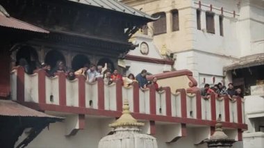 Kathmandu, Nepal - 14 November 2019: A crowd of nepalese people, relatives bending over a balcony at a temple. Kathmandu, Nepal. Smoke. Rite on the Bagmati River before a cremation in Pashupatinath.