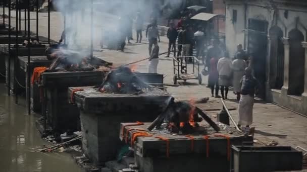 Kathmandu, Nepal - 14 November 2019: Cremation ceremony near Pashupatinath temple in Kathmandu, Nepal. People walking by. Death corpses burning. — Stok video