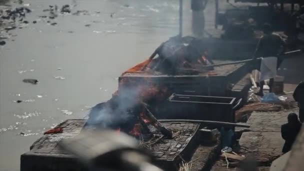 Kathmandu, Nepal - 14 November 2019: Cremation ceremony near Pashupatinath temple in Kathmandu, Nepal. A man with shovel. — Stockvideo