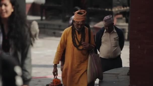 Катманду, Непал - 14 ноября 2019 года: Непальский мужчина среднего возраста в оранжевой традиционной одежде идет по улицам Катманду, Непал . — стоковое видео