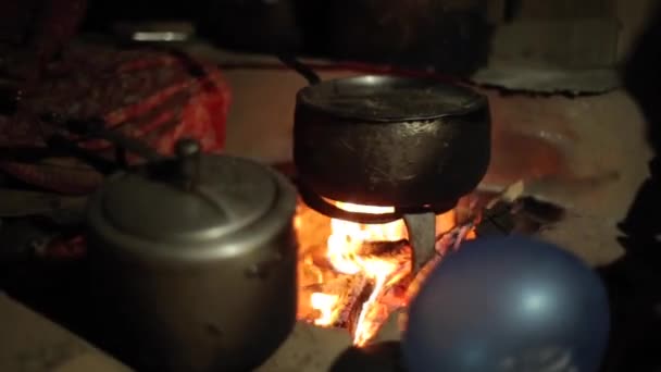 En närbild på en gammal vattenkokare, kastrull placerad ovanför eld. Nepalesisk by. — Stockvideo