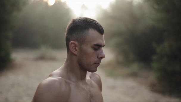 Närbild porträtt av ung atletisk kille med naken bål står i skogen och gör andas övningar. ångan kommer från munnen. Långsamma rörelser — Stockvideo