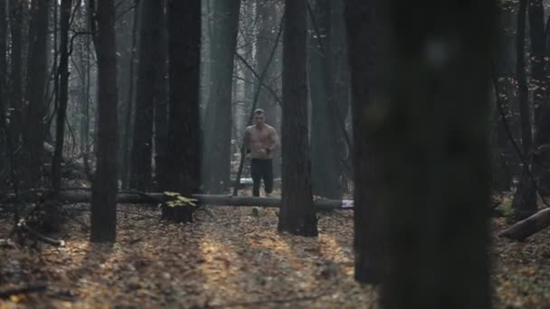 Schnell laufender muskulöser Mann mit nacktem Oberkörper. junger kaukasischer Läufer im Wald. Blick zwischen Bäumen — Stockvideo