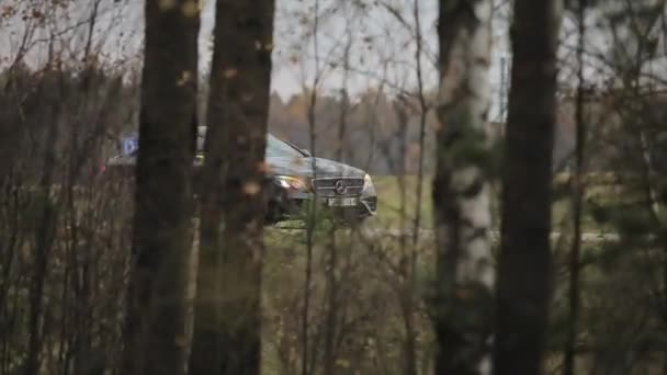 Минск, Беларусь - 11 ноября 2019 года: автомобиль быстро едет на фоне леса. вид с деревьев — стоковое видео