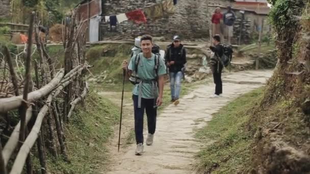 Kathmandu, Nepal - 19. November 2019: Ein Tourist spaziert durch ein nepalesisches Dorf. Lächelnd in die Kamera. Rucksäcke. Nepal. — Stockvideo
