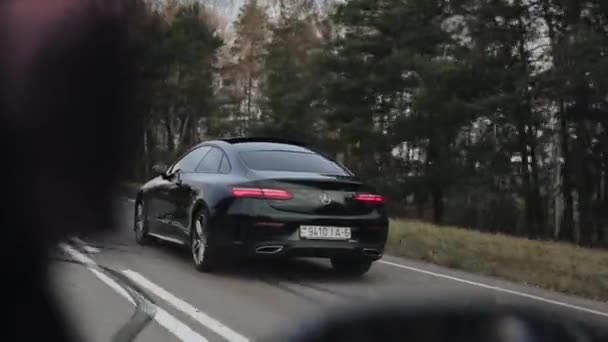 Minsk, Belarus - 11 Kasım 2019: Araba tarlalar ve ormanlar boyunca uzanan kırsal bir yolda ilerliyor. Siyah Mercedes E-Sınıfı Coupe — Stok video