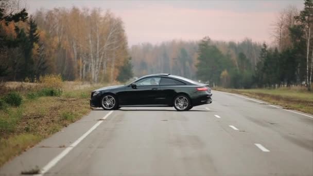 Минск, Беларусь - 11 ноября 2019 года: автомобильные прогулки по проселочной дороге. Черный Mercedes E-класса Coupe — стоковое видео