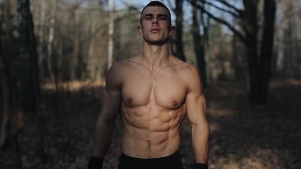 森の中の大きな筋肉の男性選手は、筋肉のトップレスと実行を示しています。スローモーション — ストック動画