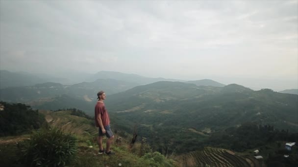 A young caucasian man standing on the top of a mountain, hill in Nepal. Cloudy, nature. — Stock Video