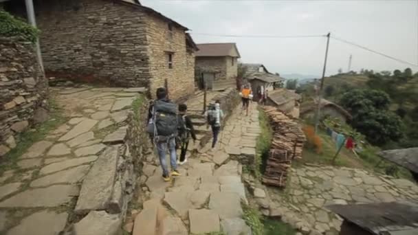 Skupina lidí, turistů kráčejících po vesnické stezce v Nepálu. Batohy. Nepál. Zadní pohled. — Stock video