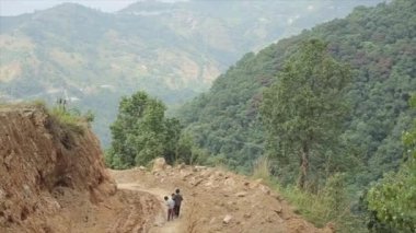 Katmandu, Nepal - 14 Kasım 2019: Çocuklar Nepal 'de bir dağ yolunda tek başlarına yürüyorlar. Nepal yeşil dağlarının, ormanların, bitkilerin, ağaçların manzarası.
