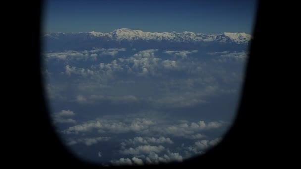Ein Blick aus einem Flugzeugfenster auf Schneeberge und Wolken. — Stockvideo