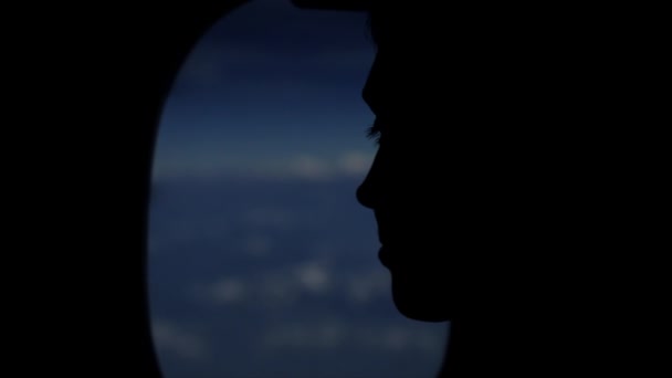 Una persona silueta mirando por la ventana de los aviones al cielo, nubes. Vista cercana. Características faciales . — Vídeos de Stock