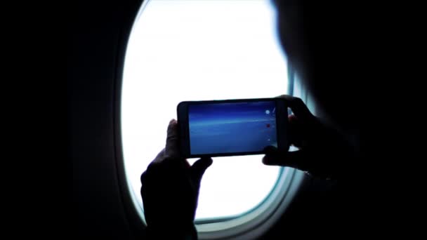 Een silhouet van persoon filmend bergen en bewolking van een vliegtuig venster. — Stockvideo