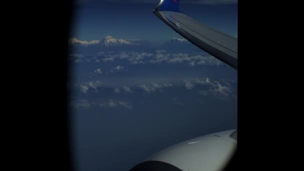 Θέα από ένα παράθυρο αεροπλάνου σε βουνά, σύννεφα, μηχανή αεροπλάνου, φτερό. Ιμαλάια. Έβερεστ — Αρχείο Βίντεο