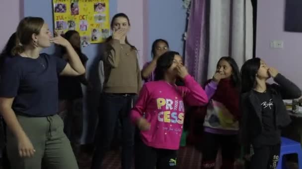 Kathmandu, Nepal - 19. November 2019: Junge lächelnde nepalesische Mädchen tanzen in einem Raum mit kaukasischen Freiwilligen. Spaß haben. — Stockvideo